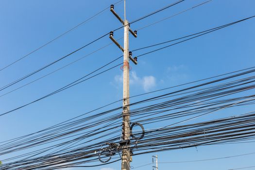 Electric pole power lines and messy wires with blue sky,Thailand