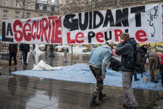 FRANCE, Paris : A picture is taken of a banner reading Security leading the People referring to the French historic painting Liberty leading the People as people join the Nuit Debout or Standing night movement at the Place de la Republique in Paris on April 2, 2016. A few hundred people rallied to demand the halt of home evictions which can begin the day after the end of the French winter break, after which tenants can be evicted from their homes. They also gathered to show their opposition to the labor reform law in the wake of the nationwide demonstration which took place on March 31, 2016.