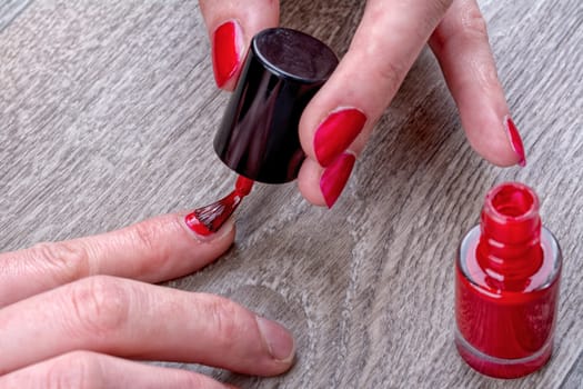 Close-up of female hands painting red nail varnish
