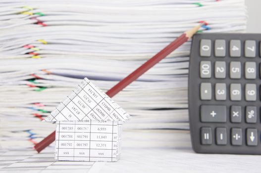 Close up house on finance account have blur pencil lean calculator and overload of paperwork with colorful paperclip as background.