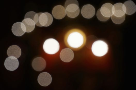 White bokeh glitter of Chinese shrine housing a statue in the night background.