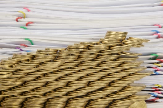 Step pile of gold coins collapse with pile of paperwork as background.