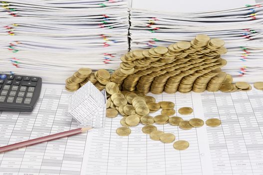 Pencil and bankruptcy of house on finance account have step pile of gold coins collapse with calculator and pile of paperwork as background.