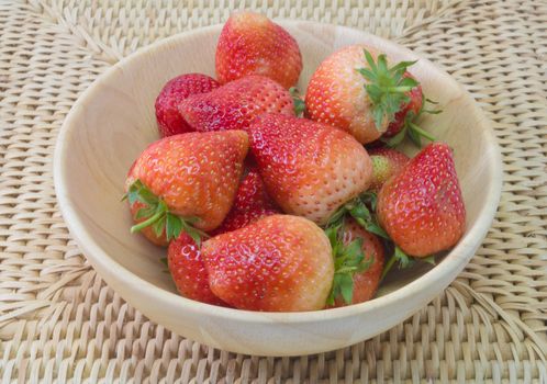 fresh strawberry in wooden bowl on wickerwork background