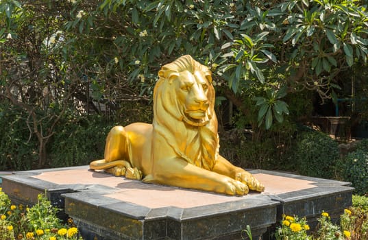 Sculpture of golden lion lying on a rock