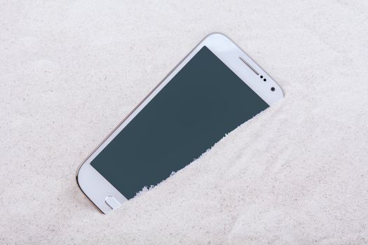 Mobile phone buried in the grey sand