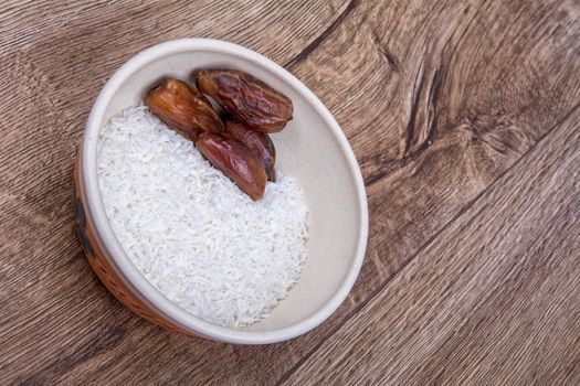 The dish with grated coconut and dried dates on a wooden background