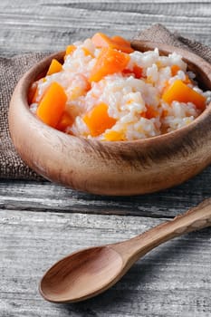 Porridge with pumpkin in a stylish wooden bowl, rustic