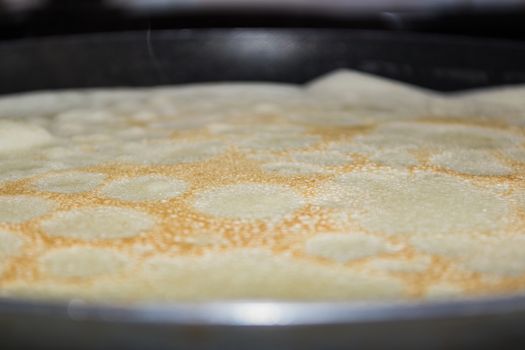 Frying pan with pancake baking on it