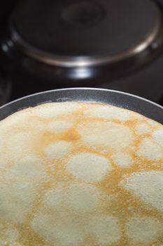 Frying pan with pancake baking on it