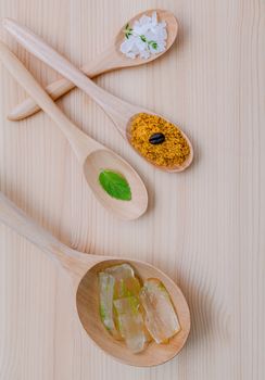 Alternative skin care and homemade scrubs aloe vera and sea salt in wooden spoons  set up on wooden table.