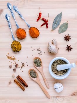 Assorted of dried spices white pepper,cumin ,bay leaf,cinnamon,star anise,thyme,ginger ,chili ,garlic ,rosemary and fennel seeds with white mortar on wooden background.