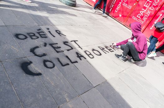 FRANCE, Paris: A militant of the Nuit Debout or Standing night movement puts Obeying is collaborating graffiti on street concrete as hundreds hold a general assembly to vote about the developments of the movement at the Place de la Republique in Paris on April 3, 2016. It has been four days that hundred of people have occupied the square to show, at first, their opposition to the labour reforms in the wake of the nationwide demonstration which took place on March 31, 2016. 