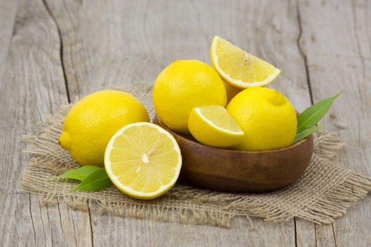 fresh lemons in a bowl on wooden background