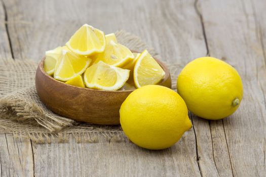 fresh lemons in a bowl on wooden background