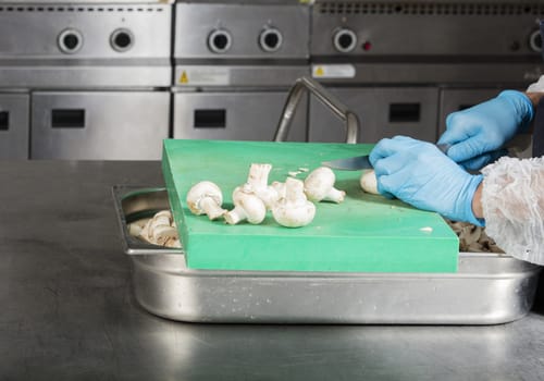 chef preparing food and cutting mushrooms in a restaurant kitchen