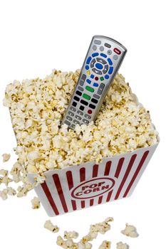 Container full of popcorn with remote control.  Isolated on white. Watch movies at home concept.