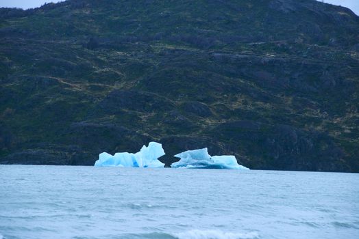 a blue iceberg from a glacier was floating in lake grey