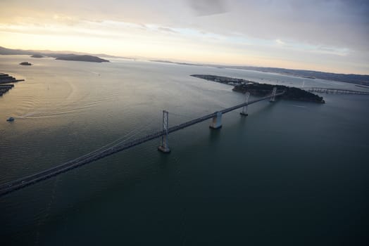 an aerial view of bay bridge near san francisco downtown during sunset, taken from a helicopter 