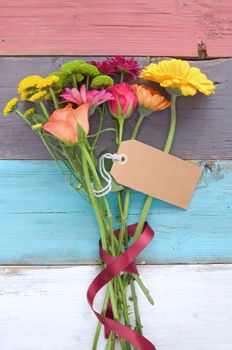 Assorted flowers with blank gift label on wooden background