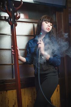 Concept: leisure lifestyle. Beautiful young woman with hookah in a bar restaurant