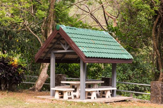 wooden gazebo with a green roof in the park