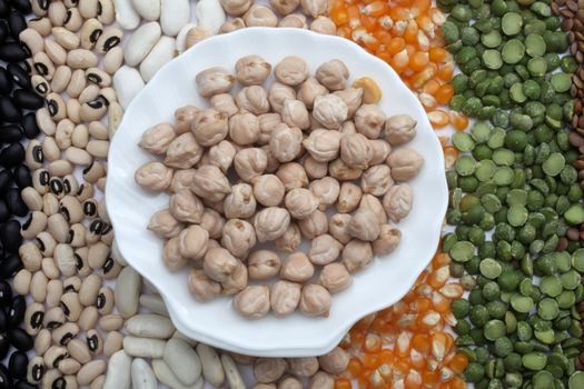 Ceramic plate with chickpeas over seeds and grains background