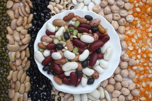 Ceramic plate with mixed beans over seeds and grains background