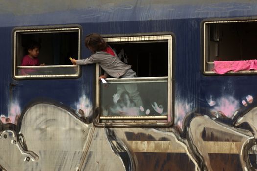 GREECE, Idomeni: Children play in a stationary wagon on April 4, 2016 at Greece-Macedonian border, near Idomeni village where thousands of people are stranded by the Balkan border blockade. Migrants return from Greece to Turkey begun under the terms of an EU deal that has worried aid groups that same day, as Athens struggles to manage the overload of desperate people on its soil. Over 51,000 refugees and migrants seeking to reach northern Europe are stuck in Greece, after Balkan states sealed their borders. Under the agreement, designed to halt the main influx which comes from Turkey, all irregular migrants arriving since March 20 face being sent back, although the deal calls for each case to be examined individually. For every Syrian refugee returned, another Syrian refugee will be resettled from Turkey to the EU, with numbers capped at 72,000.