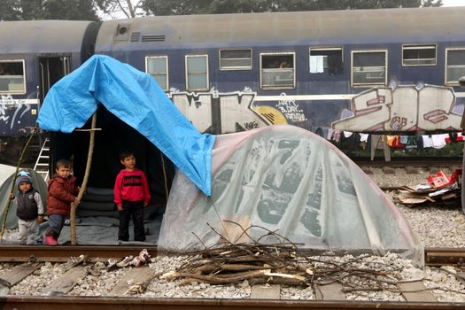 GREECE, Idomeni: Children stand next to a railway line in a makeshift camp on April 4, 2016 at Greece-Macedonian border, near Idomeni village where thousands of people are stranded by the Balkan border blockade. Migrants return from Greece to Turkey begun under the terms of an EU deal that has worried aid groups that same day, as Athens struggles to manage the overload of desperate people on its soil. Over 51,000 refugees and migrants seeking to reach northern Europe are stuck in Greece, after Balkan states sealed their borders. Under the agreement, designed to halt the main influx which comes from Turkey, all irregular migrants arriving since March 20 face being sent back, although the deal calls for each case to be examined individually. For every Syrian refugee returned, another Syrian refugee will be resettled from Turkey to the EU, with numbers capped at 72,000.