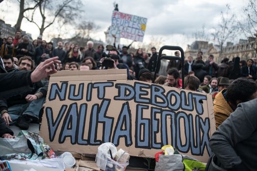 FRANCE, Paris: A picture is taken of a placard reading Standing night, Valls on his knees as hundreds of militants of the Nuit Debout or Standing night movement hold a general assembly to vote about the developments of the movement at the Place de la Republique in Paris on April 4, 2016. It has been five days that hundred of people have occupied the square to show, at first, their opposition to the labour reforms in the wake of the nationwide demonstration which took place on March 31, 2016. 