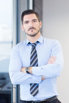 Successful team leader and business owner proudly standing with crossed arms in office. Business and entrepreneurship concept.