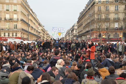 FRANCE, Paris: A man holds a placard reading Refugees welcome as hundreds of militants of the Nuit Debout or Standing night movement hold a general assembly to vote about the developments of the movement at the Place de la Republique in Paris on April 4, 2016. It has been five days that hundred of people have occupied the square to show, at first, their opposition to the labour reforms in the wake of the nationwide demonstration which took place on March 31, 2016.