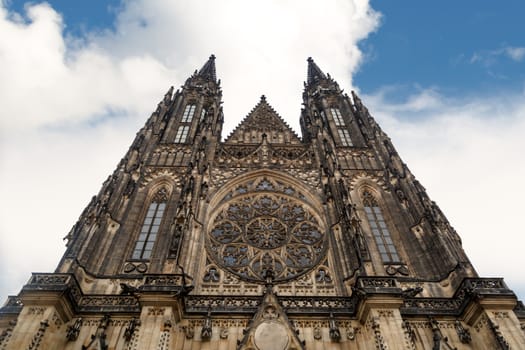 Bottom view of historical gothic St. Vitus Cathedral in old town of Prague, found in 1344, on cloudy blue sky background.