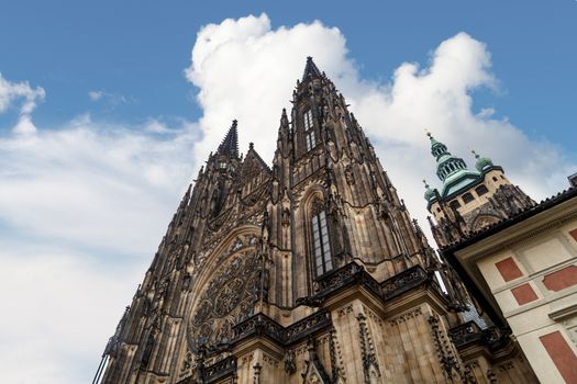 Bottom view of historical gothic St. Vitus Cathedral in old town of Prague, found in 1344, on cloudy blue sky background.