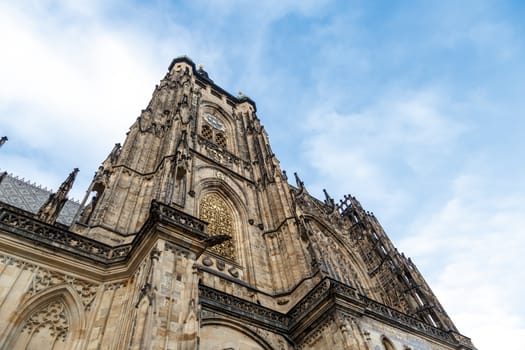 Bottom view of historical gothic St. Vitus Cathedral in old town of Prague, found in 1344, on cloudy blue sky background.