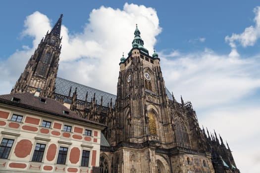Bottom view of historical gothic St. Vitus Cathedral in old town of Prague, found in 1344, on cloudy blue sky background.