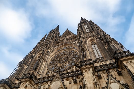 Bottom view of historical gothic St. Vitus Cathedral in old town of Prague, found in 1344, on cloudy blue sky background.
