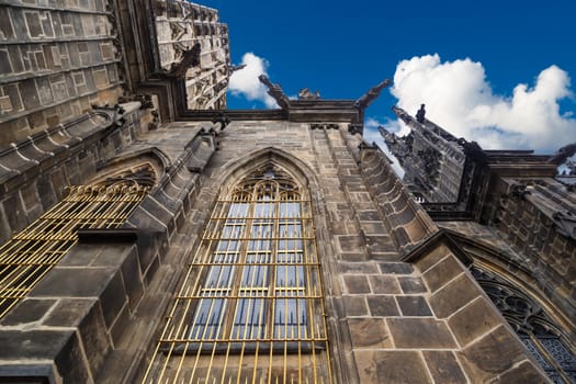 Close up detailed view of historical gothic St. Vitus Cathedral in old town of Prague, found in 1344, on cloudy blue sky background.