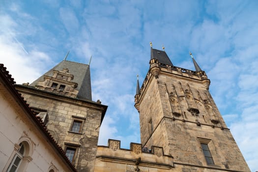 Close up detailed historical gothic stone tower view in Prague, on cloudy blue sky background.