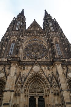 Bottom view of historical gothic St. Vitus Cathedral in old town of Prague, found in 1344, on cloudy blue sky background.