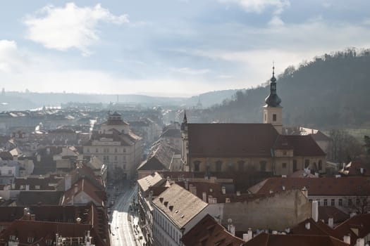 General top view of Prague cityscape view with historical gothic buildings around, on cloudy sky background.