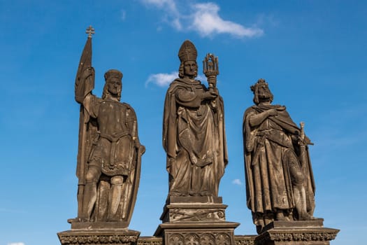 Close up detailed view of historical gothic granit sculptures on Charles Bridge in Prague, on bright blue sky background.
