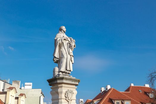 Close up detailed view of historical gothic granit sculptures on Charles Bridge in Prague, on bright blue sky background.