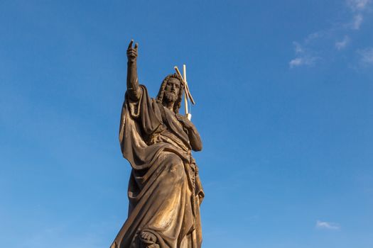 Close up detailed view of historical gothic granit sculptures on Charles Bridge in Prague, on bright blue sky background.