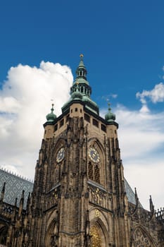 Bottom view of historical gothic St. Vitus Cathedral in old town of Prague, found in 1344, on cloudy blue sky background.