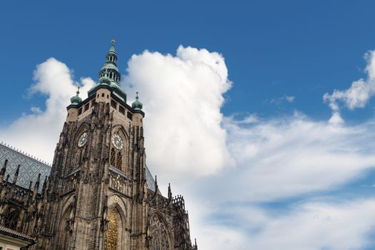 Bottom view of historical gothic St. Vitus Cathedral in old town of Prague, found in 1344, on cloudy blue sky background.