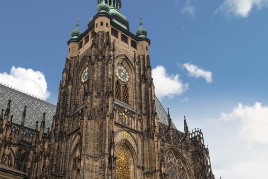 Bottom view of historical gothic St. Vitus Cathedral in old town of Prague, found in 1344, on cloudy blue sky background.
