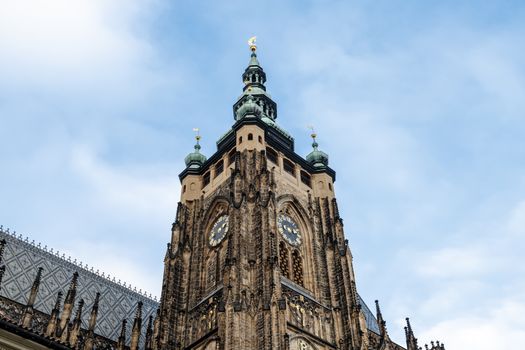 Bottom view of historical gothic St. Vitus Cathedral in old town of Prague, found in 1344, on cloudy blue sky background.