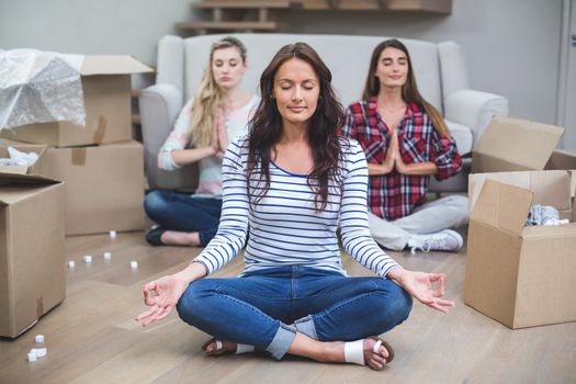 Three friends performing yoga together in their new house